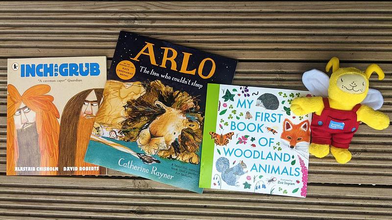 Three books (Inch and Grub, Arlo the lion who couldn't sleep, and My First Book of Animals) lying next to Bookbug doll